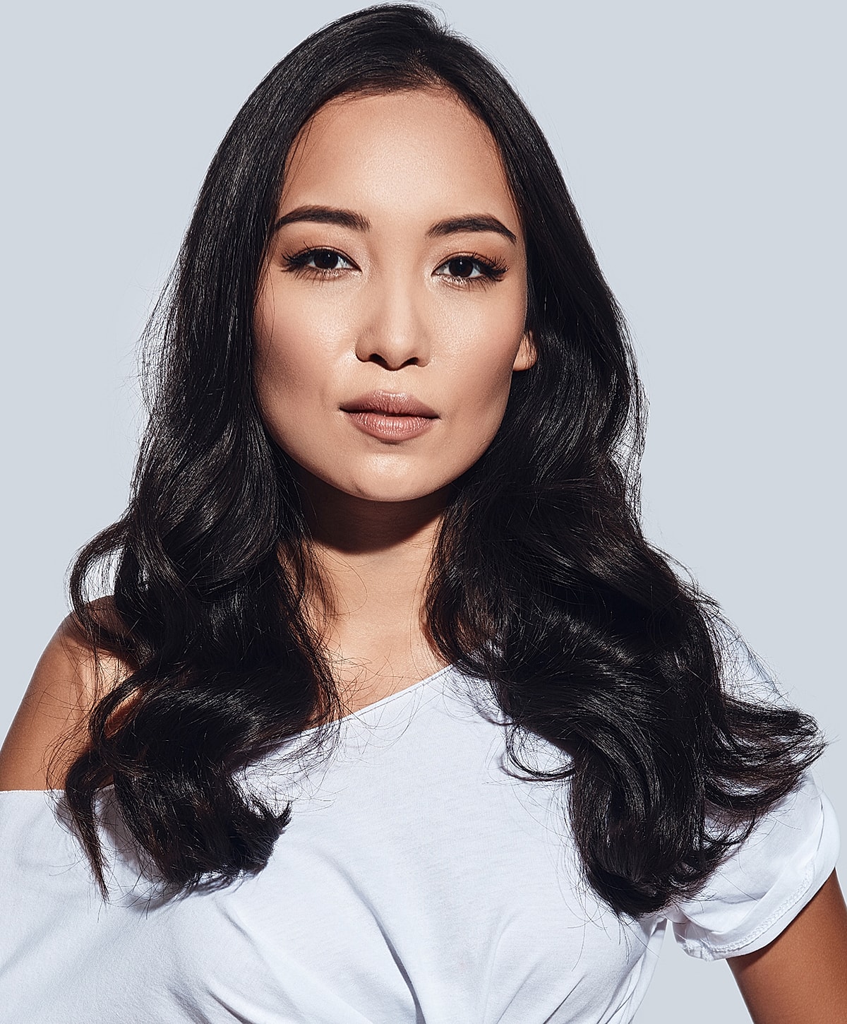 Woman with wavy hair wearing a white shirt.