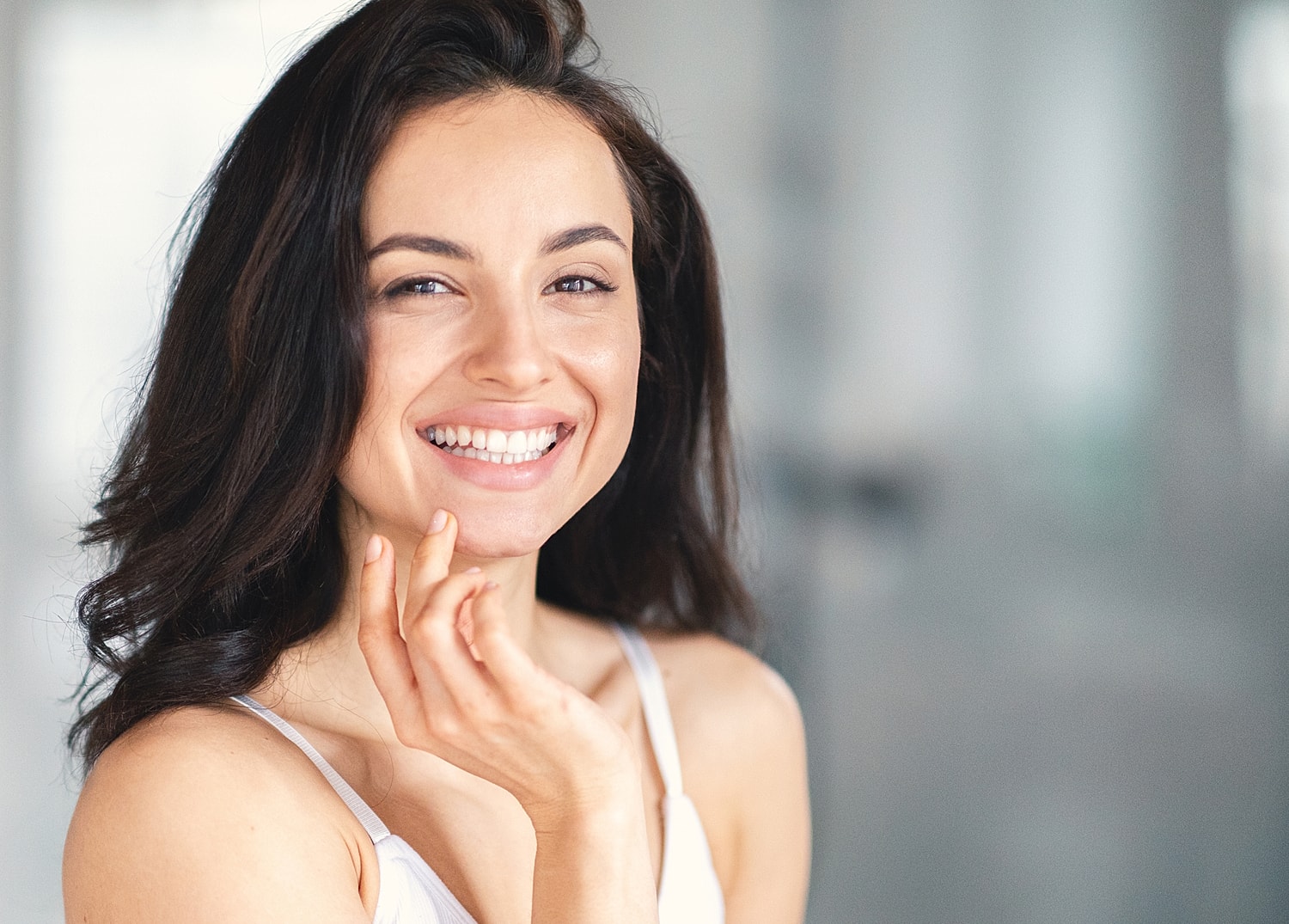 Smiling woman touching her face indoors.