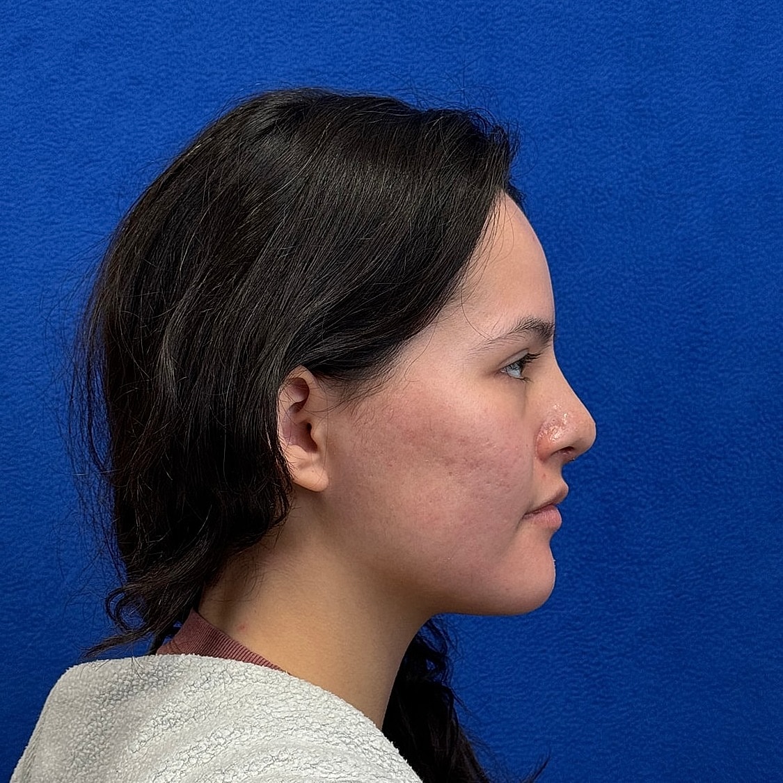 Profile of a young woman against blue background.