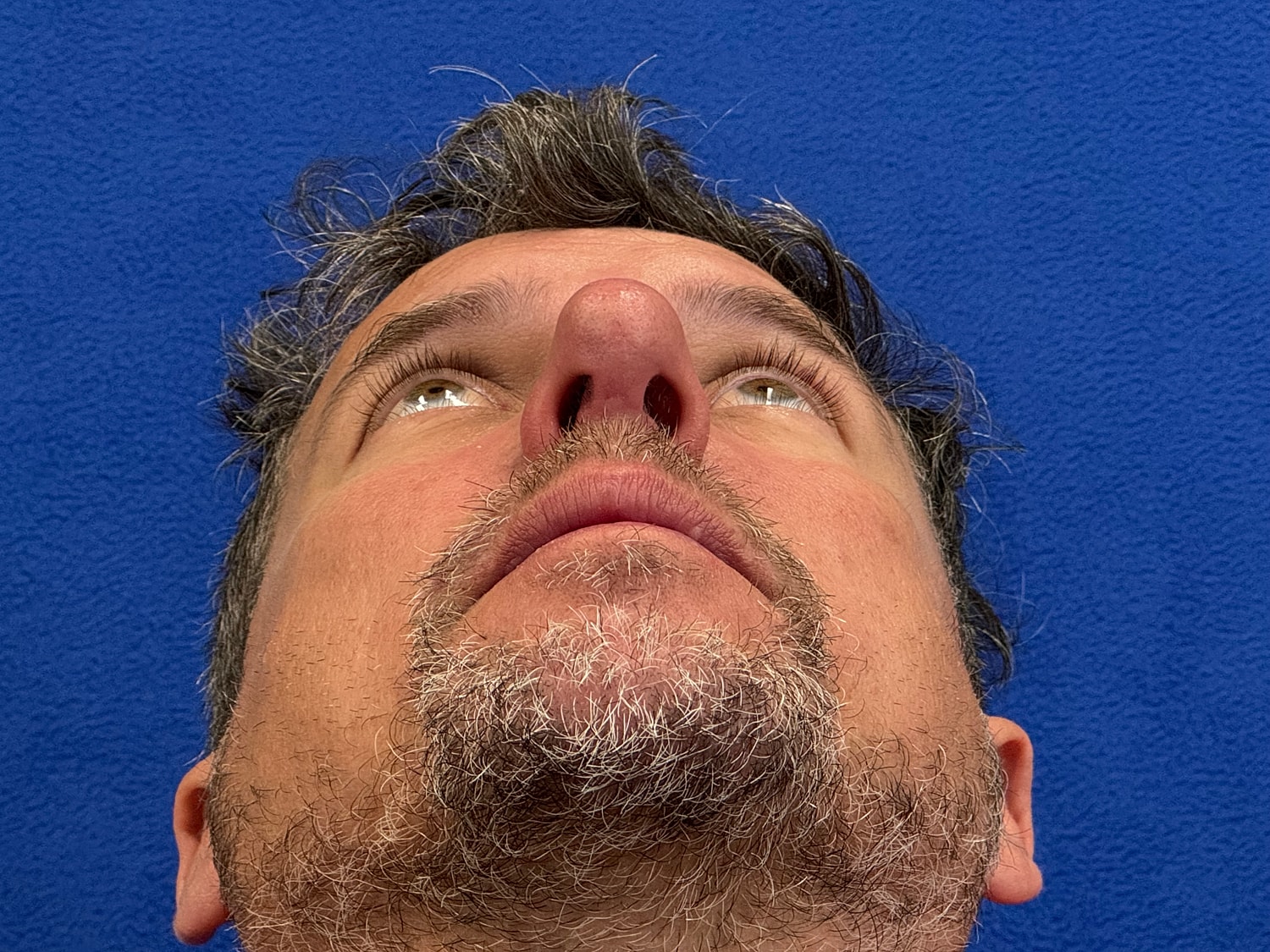 Man looking upward against blue background.
