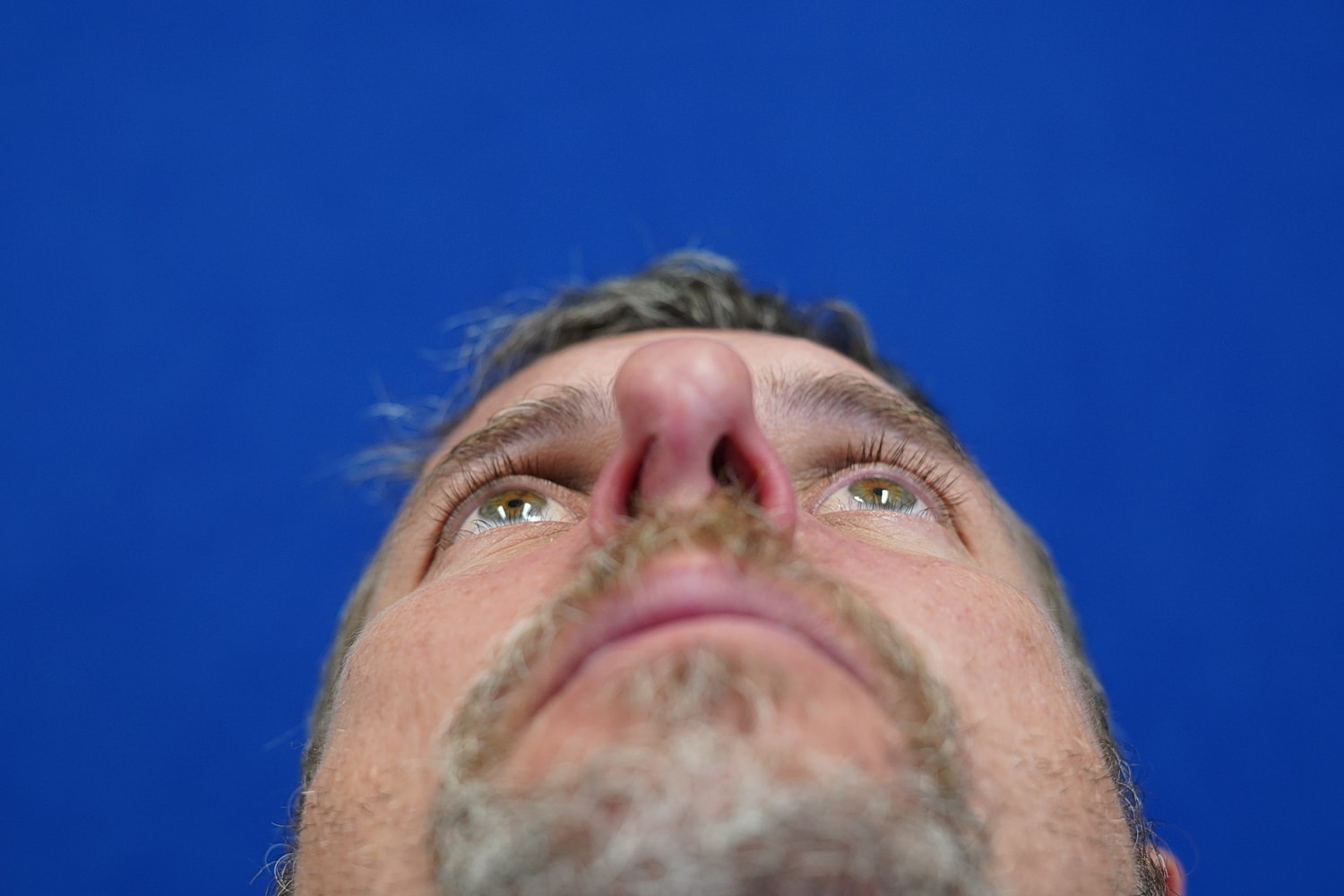 Close-up of a man's face against blue background.
