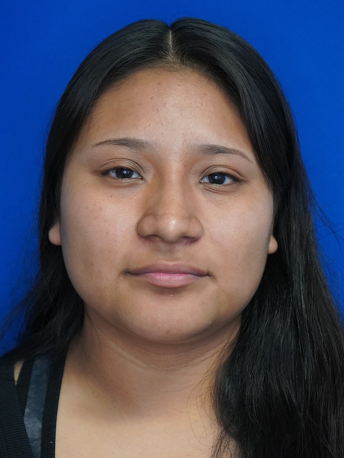 Portrait of a young woman against blue background.