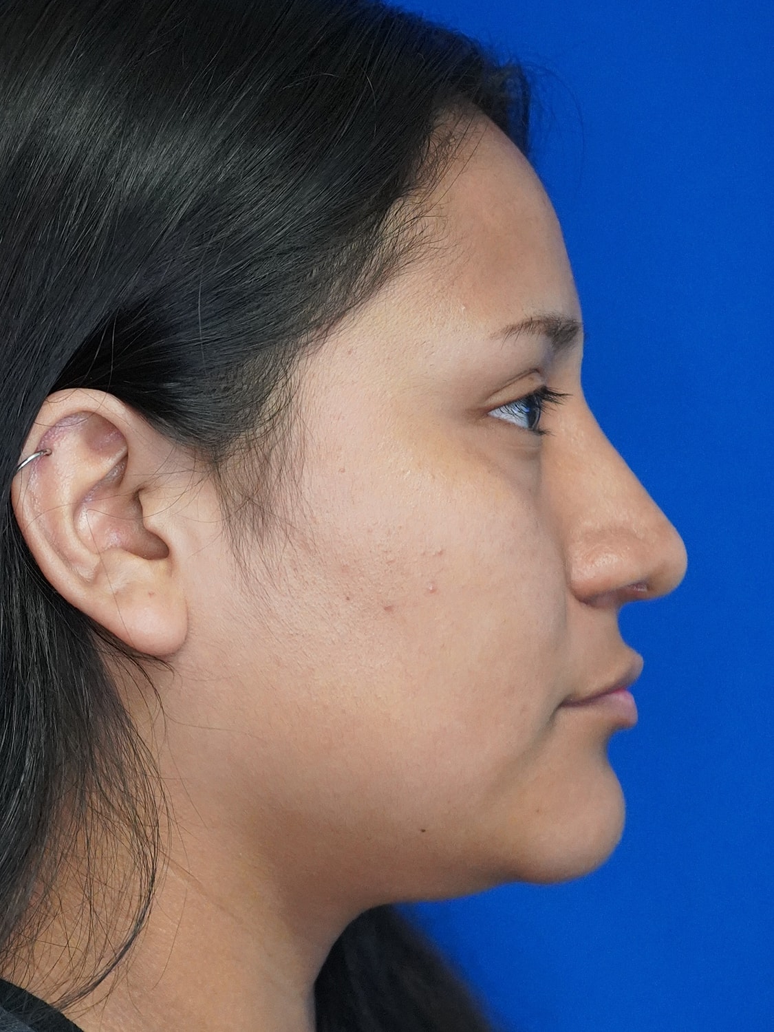 Profile view of a woman against blue background.