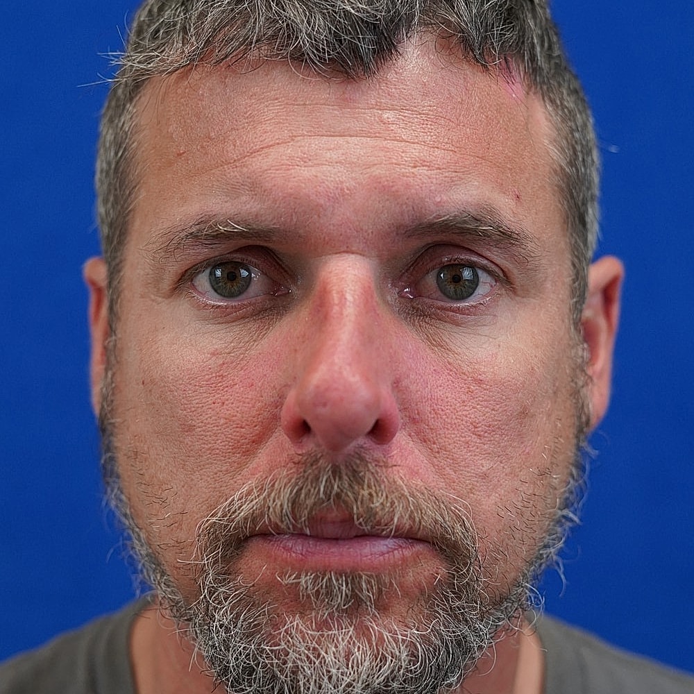 Man with beard against blue background.