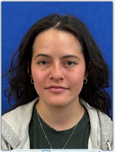 Young woman with dark hair against blue background.