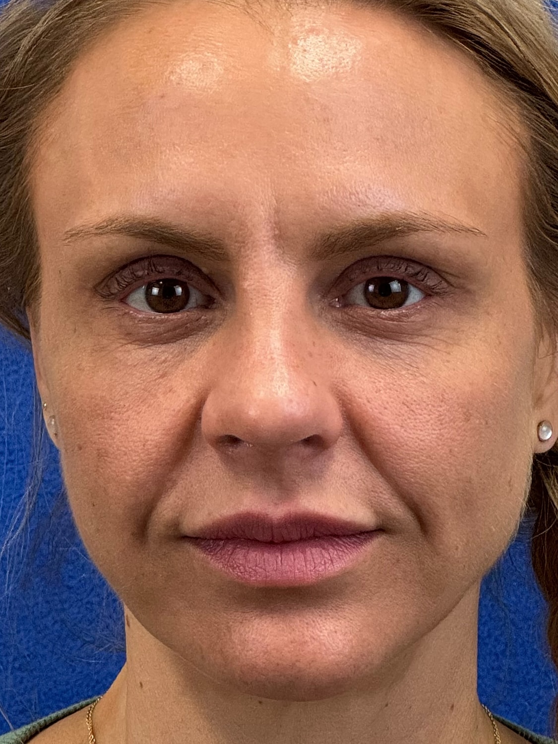 Close-up portrait of a woman against blue background.