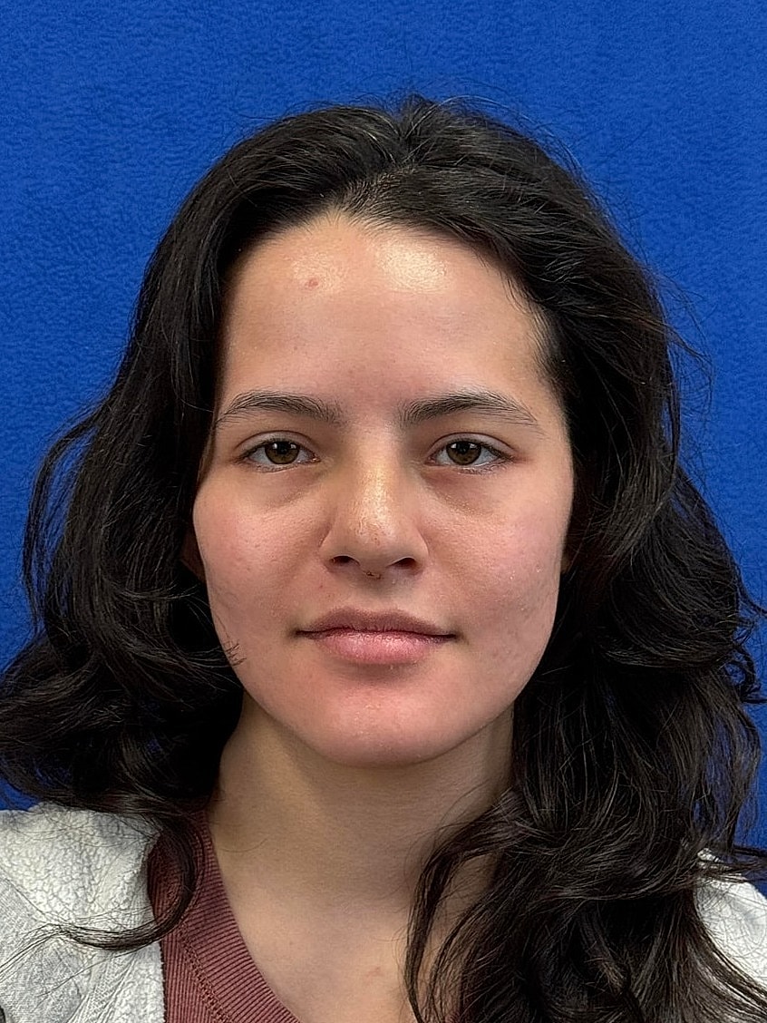 Young woman with long, wavy hair and neutral expression.